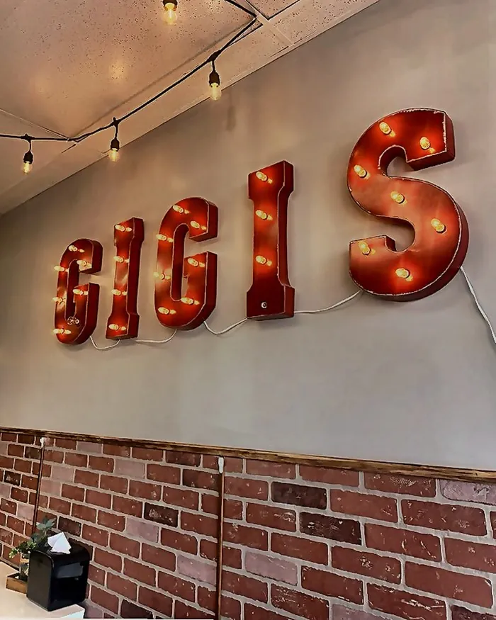 Illuminated GIGI'S marquee letters on the dining room brick wall in Long Branch